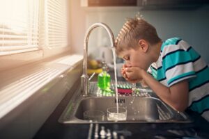 Child drinking water from sink with reverse osmosis water filter.